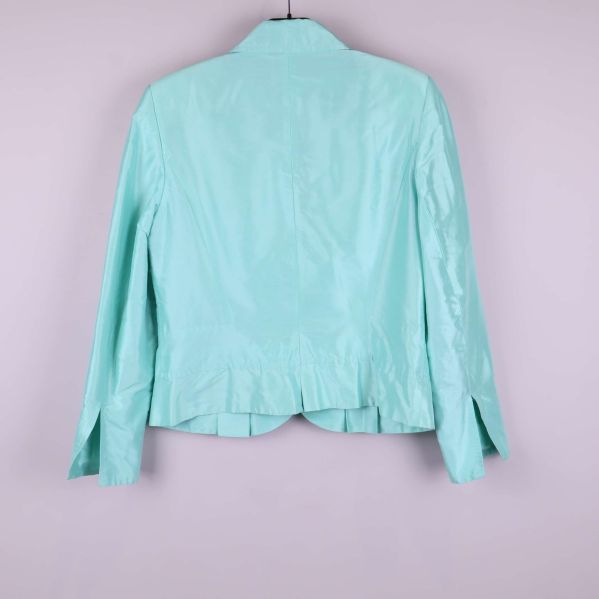 Baksidan av ljusblå blazer visas mot en grå bakgrund