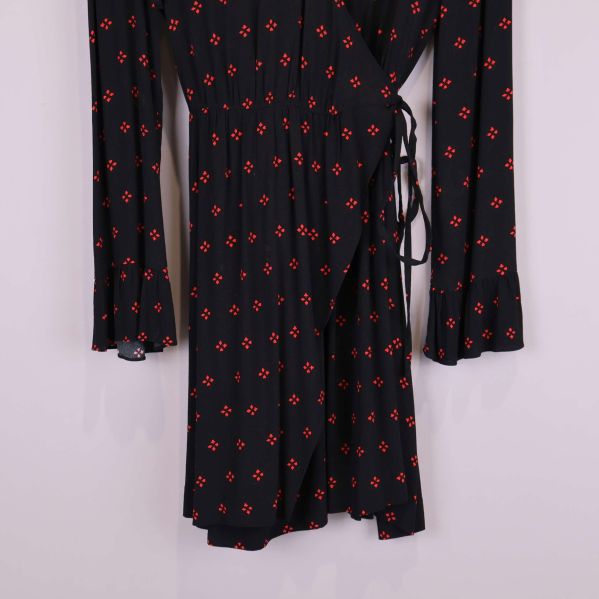 Närbild på kjoldel och volangkant på svart mönstrad klänning