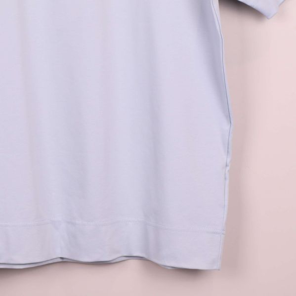 Närbild på nederkant av ljusst blå t-shirt