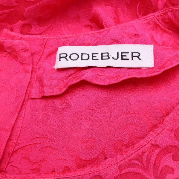 Närbild på Rodebjer-logotyp i blusens krage