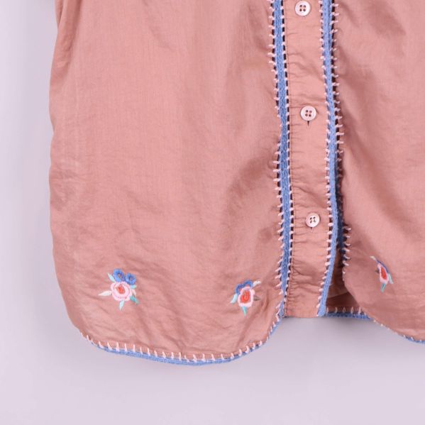 Närbild på nederkant fram med broderat blommönster
