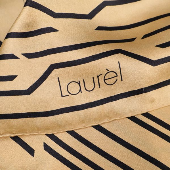 Närbild på Laurèl-logga på beige scarf med svarta linjer