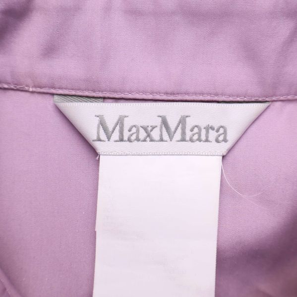 Närbild på MaxMara-logotypen i kragen på lila skjorta