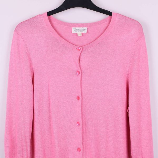 Närbild på övre delen av rosa cardigan och knappar