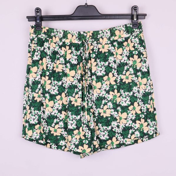 Shorts med grönt, vitt och beige blommönster hänger på galge