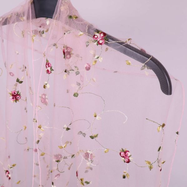 Närbild på broderade blommor och transparent tyg