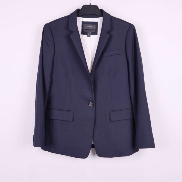 Mörkblå blazer på galge mot ljus bakgrund med stängd knapp