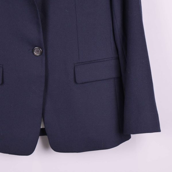 Detalj närbild på knapp och fickor nedtill av blazer