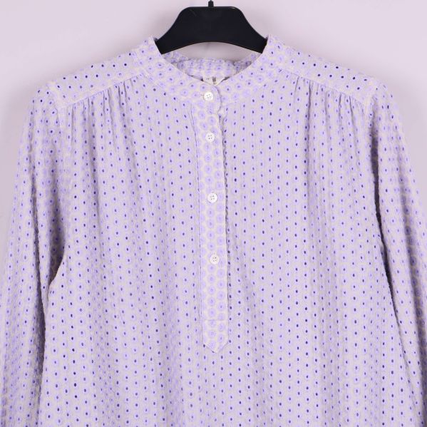 Närbild på blusens knappar och broderidetaljer framtill