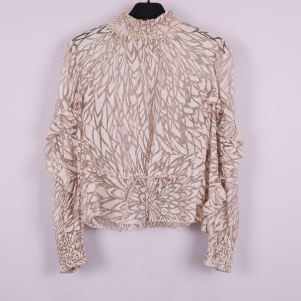 Framsidan av mönstrad beige blus med volanger