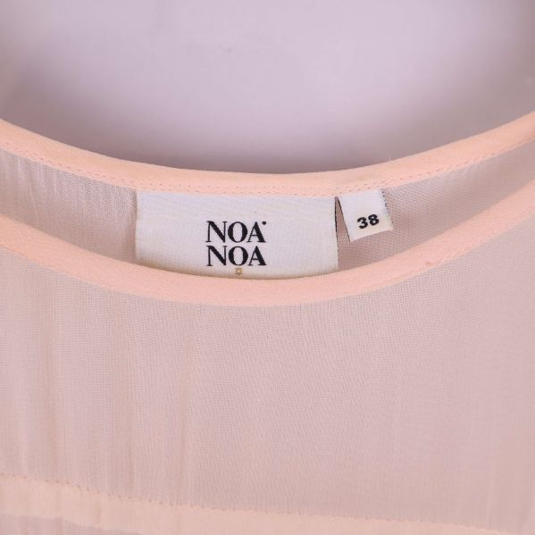 Närbild på Noa Noa-logga och storlekslapp i halslinningen
