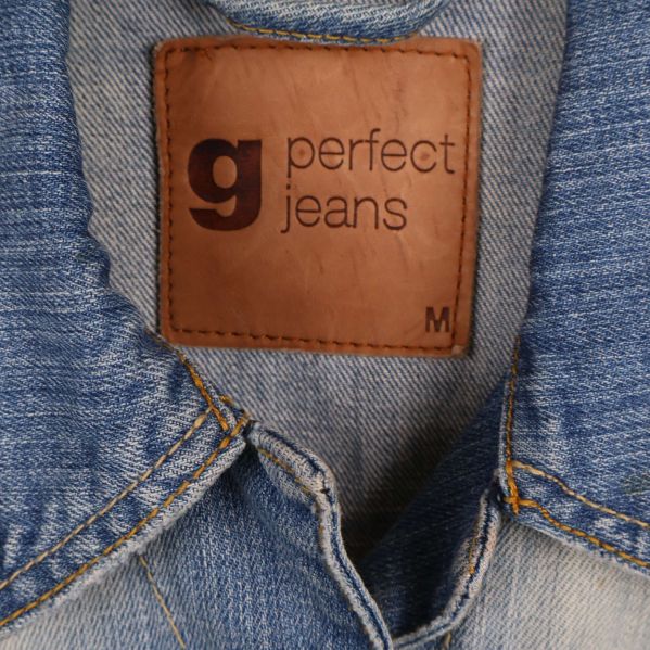 Närbild på brun etikett med texten g perfect jeans