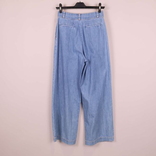 Baksida av ljusblå jeans upphängda på galge