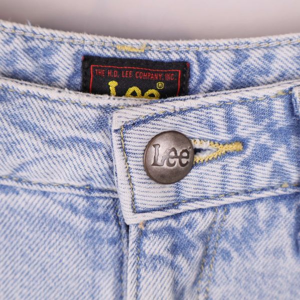 Närbild på Lee-knapp och label framtill på jeansen