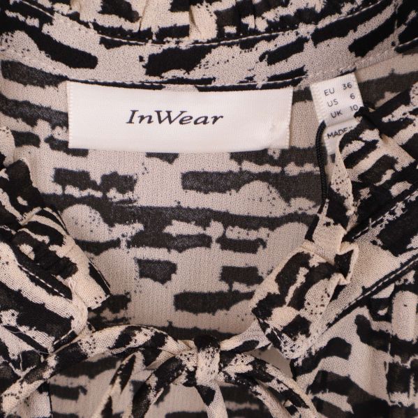 Närbild på InWear-logga och storleksetikett i blusens krage