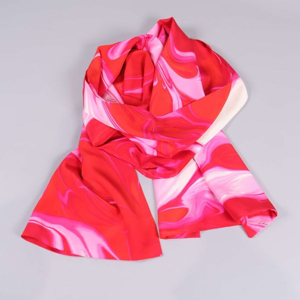 Scarfen liggande lös med tydliga swirl-print i rosa och rött