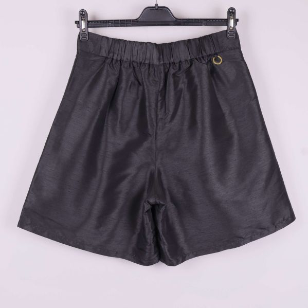 Baksida på svarta shorts med resår och metallsmycke