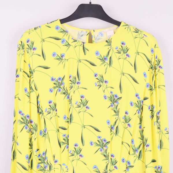 Närbild av gul klännings överdel med blå blommönster