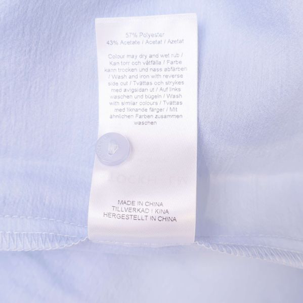 Materialetikett visar 57% polyester och 43% acetat