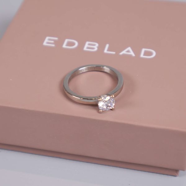 Ring i blank metall med gnistrande sten på ask