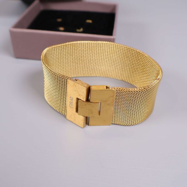Närbild på armbandets guldfärgade lås och meshstruktur