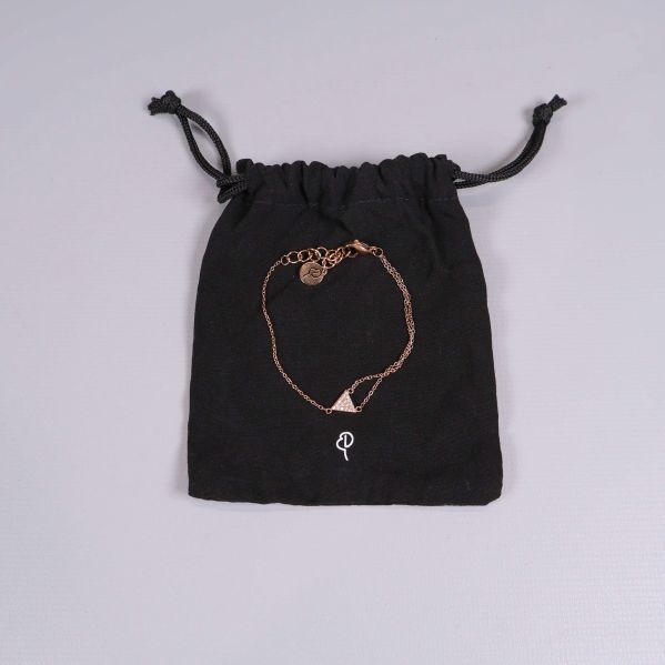 Armband i guldton på svart förvaringspåse