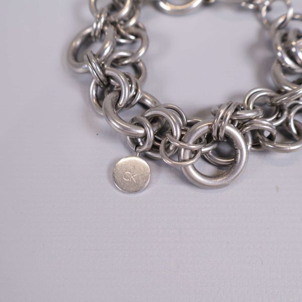 Detalj på armbandet med rund bricka och länkstruktur