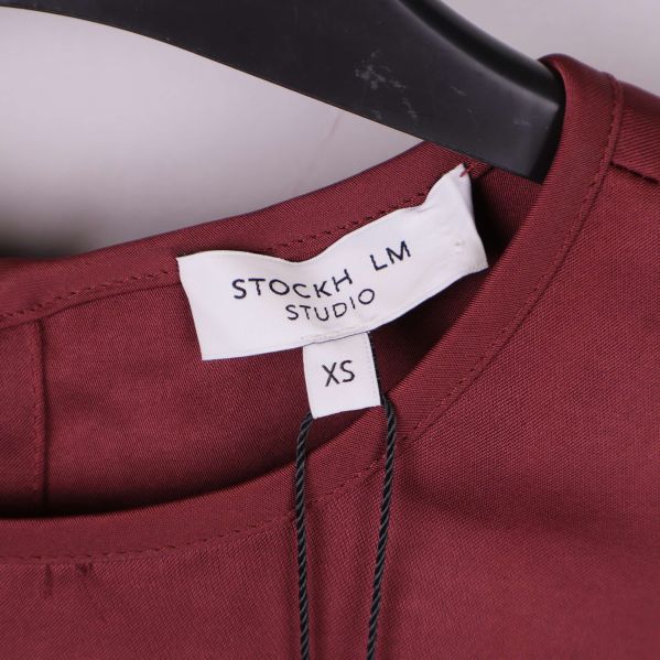 Blusens storleksetikett med texten STOCKH LM STUDIO XS