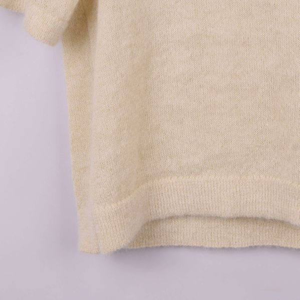 Närbild på nederkanten av beige stickad topp
