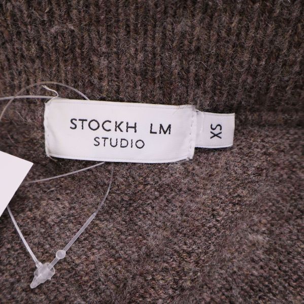 Närbild på etikett med texten STOCKH LM STUDIO och storlek XS