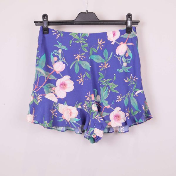 Framsidan av blå shorts med blommigt mönster och volangkant