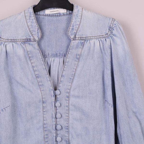 Närbild på krage och knappar på denimblus