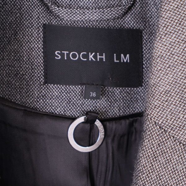 Etikett med STOCKH LM och storlek 36 i nacken på grå blazer