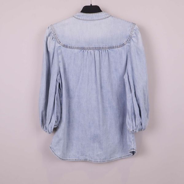 Baksida av ljus denimblus med puffärm