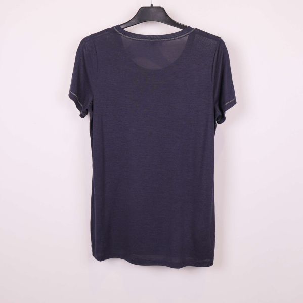 Baksida av blå t-shirt i sin helhet mot ljus bakgrund