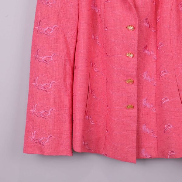 Närbild på ärm och knappar av rosa broderad kavaj