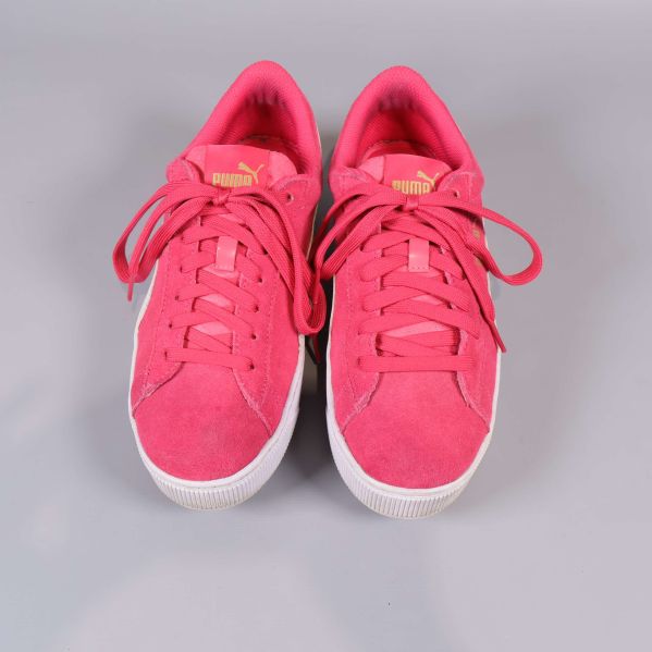 Framifrån vy av rosa Puma sneakers med snörning