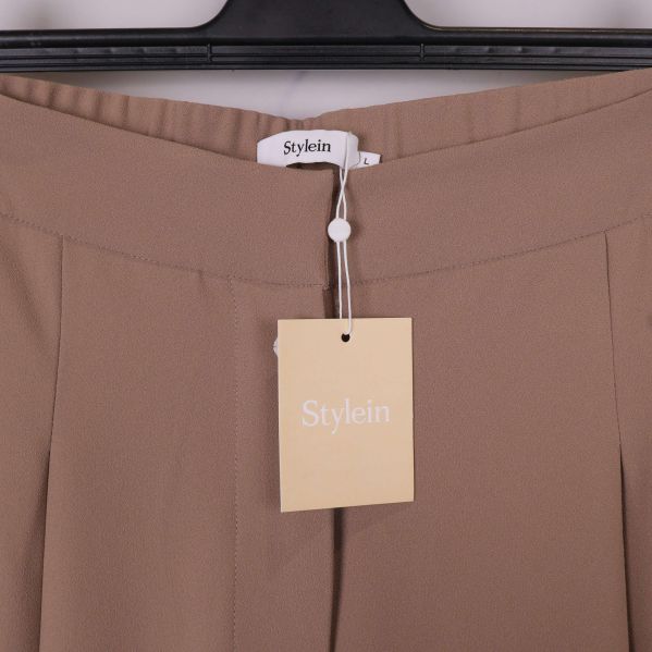 Närbild på midja och Stylein-hängare på beige byxa