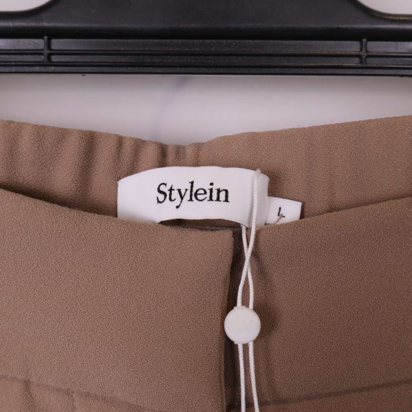 Närbild på Stylein-logga i midjan på beige byxa