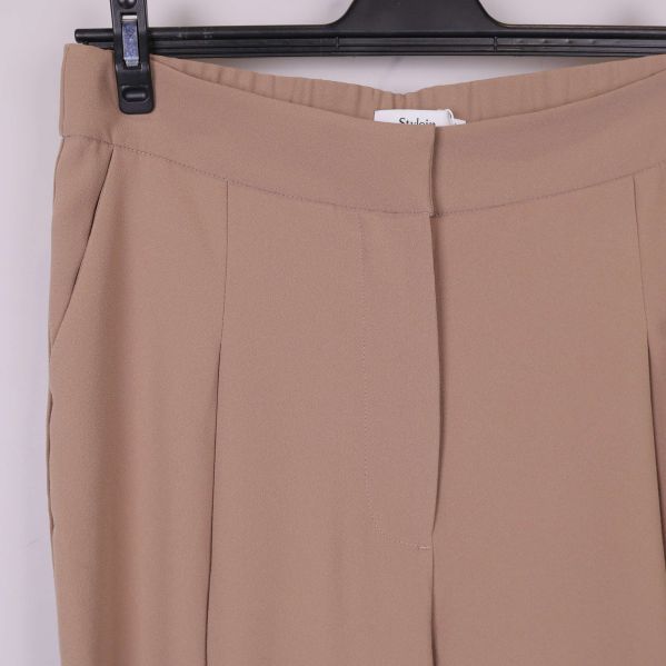 Detaljbild av framfickor och front på beige byxa