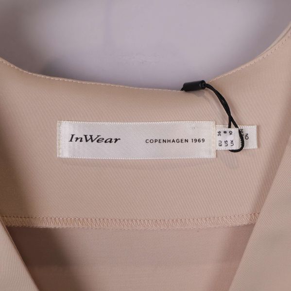 Närbild på InWear-märkesetikett i halsen på beige topp