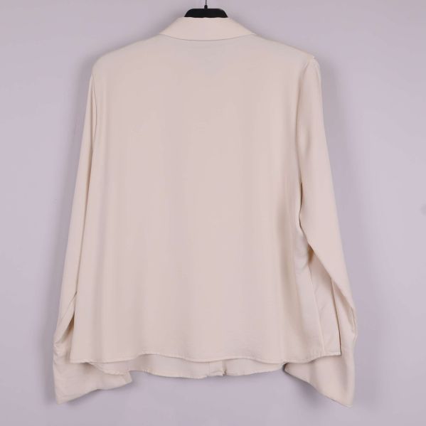Baksida av beige blus med slät design och vida ärmar