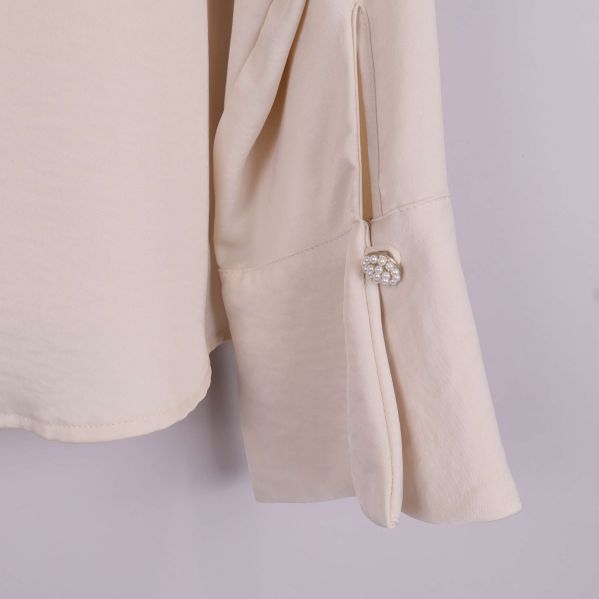 Manschett med pärldekor på beige blus med lång ärm