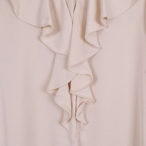 Närbild på volang framtill på beige blus