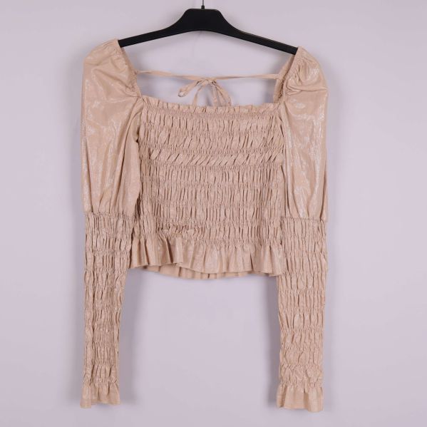 Beige smockad blus sett framifrån på galge