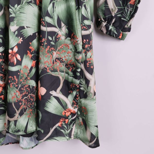 Detaljbild på kjoldelens blommiga tyg och elastisk ärmmudd