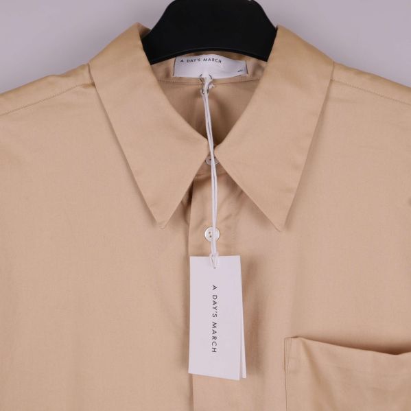 Beige skjorta med klassisk spetsig krage och synliga knappar