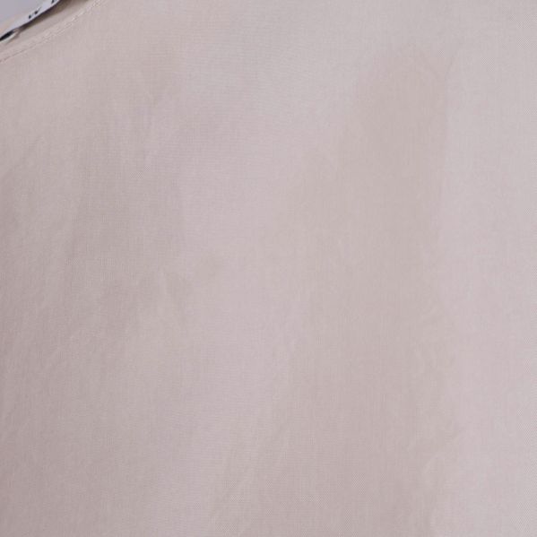Närbild på blusens material och färg i ljus ton