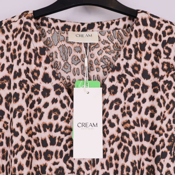 Närbild på etikett med Cream-logga i nacken på leopardmönster