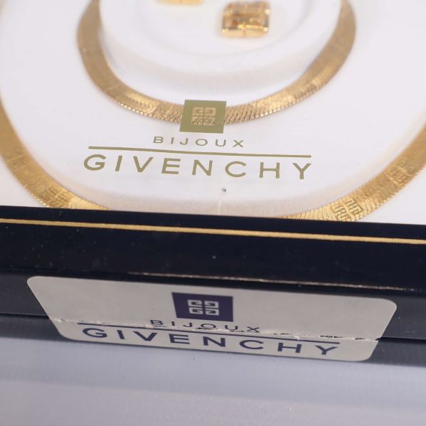 Närbild på Givenchy-logga och smycke med guldton